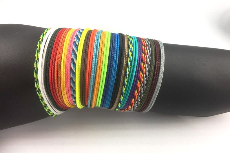 May include: A stack of colorful braided bracelets in various colors, including red, orange, yellow, green, blue, purple, and black.