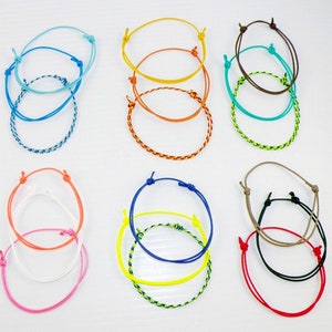 May include: A set of eight colorful friendship bracelets, each made of braided string. The bracelets are in various colors, including blue, orange, yellow, green, brown, and red.