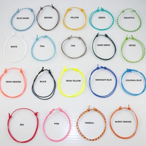 Puede incluir: Una colección de 20 pulseras trenzadas de colores, cada una con un color y un nombre diferentes. Las pulseras están dispuestas en cuatro filas de cinco, con los nombres de cada pulsera impresos debajo. Los colores incluyen azul, verde, amarillo, naranja, rojo, rosa, marrón, negro, blanco, azul verdoso, marrón, verde oscuro, y más.