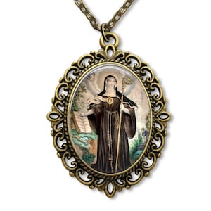 May include: A bronze oval pendant necklace featuring a cameo image of a woman in a black robe holding a staff and a book. The cameo is surrounded by an ornate filigree frame.