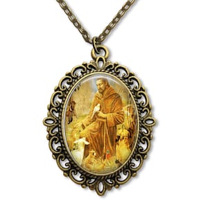 Può includere: Una collana con un ciondolo ovale in bronzo con una cornice filigranata dettagliata. Il ciondolo presenta un'immagine colorata di San Francesco d'Assisi circondato da animali.