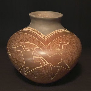 May include: A brown ceramic pot with a geometric design in white. The pot has a wide base and a narrow neck.
