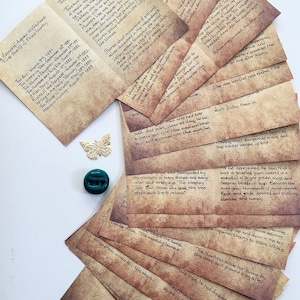 Könnte beinhalten: Ein Stapel altertümlich aussehender Papierkarten mit handschriftlichem Text. Die Karten sind gealtert und haben eine braune, pergamentartige Textur. Der Text auf den Karten ist in einer kursivschriftlichen Schrift und enthält Titel wie "The Box", "The Weeping Tree" und "The Miner's Daughter".