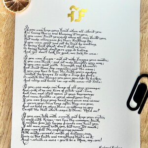 May include: A white paper sheet featuring the poem If by Rudyard Kipling written in black calligraphy. A gold logo is at the top center. A black paper clip is attached to the right side, and a dried orange slice sits in the top left corner.