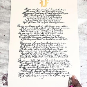 May include: A cream-colored paper sheet featuring the poem If by Rudyard Kipling written in black calligraphy ink. At the top, a gold-colored logo displays the letters FF. A pink fountain pen is positioned at the bottom right corner of the paper.