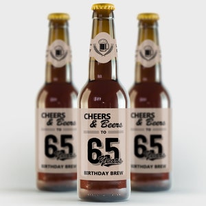 Könnte beinhalten: Drei braune Glasbierflaschen mit braunen Etiketten. Die Etiketten haben schwarzen Text, der "Cheers & Beers to 65 Years Birthday Brew" lautet.