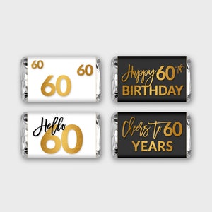 May include: Four chocolate bar wrappers with gold foil accents and black text. The wrappers feature the text "60", "Happy 60th Birthday", "Hello 60", and "Cheers to 60 Years".