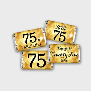 May include: Four gold foil-wrapped chocolate bars with black text. The text on the bars reads "75 & Fabulous", "Hello 75", "Cheers to Seventy Five Years", and "75".