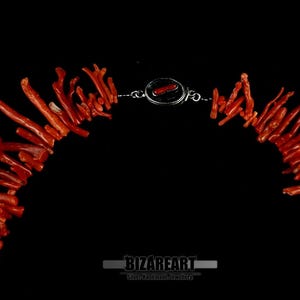 Pu&ograve; includere: Una collana realizzata con rami di corallo, con una chiusura in argento. Il corallo &egrave; di un colore rosso-arancione vibrante.