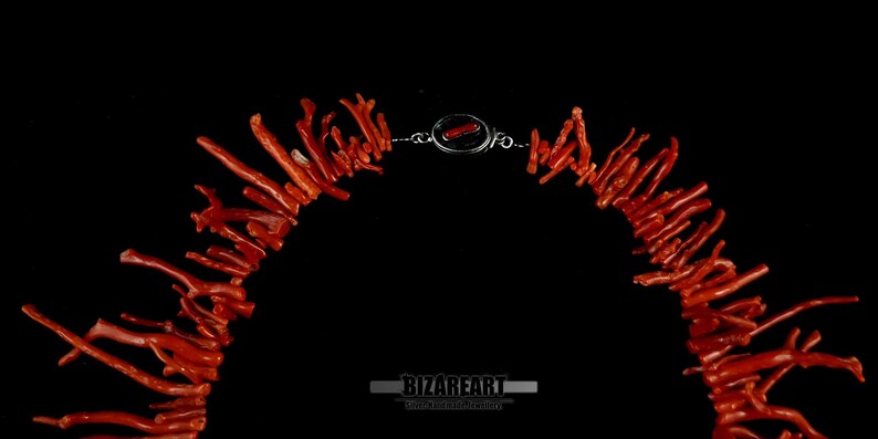 Pu&ograve; includere: Una collana realizzata con rami di corallo, con una chiusura in argento. Il corallo &egrave; di un colore rosso-arancione vibrante.