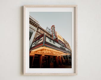 May include: A vintage movie theater marquee with the word "Tivoli" in red neon letters. The marquee is lit up with white lights and has a sign that reads "Step Into The Past" and "NYC's Greatest History Today".