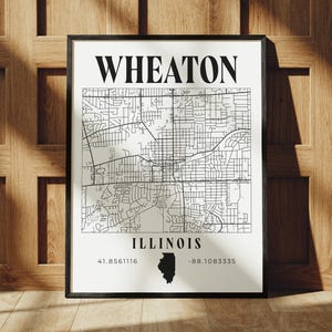 May include: Black framed print featuring a detailed map of Wheaton, Illinois. The map is in black and white, with the city name at the top and "ILLINOIS" at the bottom. Coordinates and the state outline are also included.