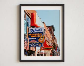 May include: A colorful sign for Robert's Western World, a honky tonk bar in Nashville, Tennessee. The sign features a red cowboy boot, a guitar, and the text "Home of the Original Broadway Honky Tonk Heaven".