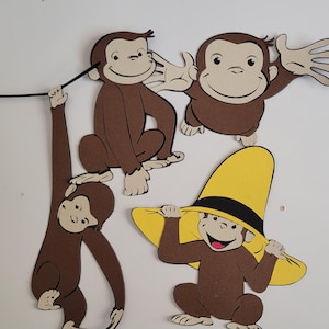 May include: Four brown paper cutouts of Curious George monkeys. One monkey is wearing a yellow hat with a black band. The monkeys are all smiling and have brown eyes.