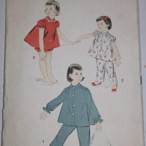 May include: A vintage sewing pattern for children's pajamas. The pattern is for size 6 and includes three different styles. The first style is a blue pajama set with ruffled cuffs. The second style is a white pajama set with a floral print. The third style is a red and white polka dot dress with a matching diaper cover. The pattern is from Advance, the easy printed pattern.