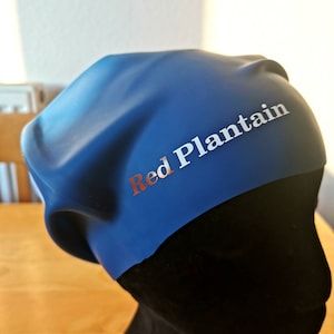 May include: A blue swim cap with the text "Red Plantain" in white lettering.