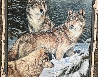 May include: A framed artwork showing three wolves in a snowy forest. The wolves have brown and grey fur, with snow on their backs. The artwork is framed with a decorative border that resembles tree bark.