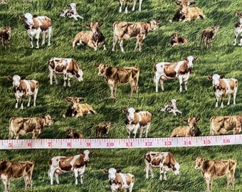 Puede incluir: Tela con un patrón repetido de vacas en un campo verde. Las vacas son marrones y blancas, en varias poses. Una cinta métrica está en la parte inferior, mostrando pulgadas.