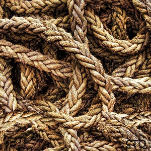 May include: A close-up of a tangled pile of thick, brown rope. The rope is woven together in a complex pattern, creating a textured and rustic look.