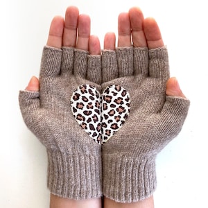以下が含まれることがあります： 手の甲にヒョウ柄のハートが付いた、茶色の指なし手袋のペアです。
