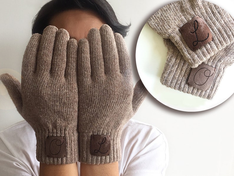 Puede incluir: Un par de guantes de punto marr&oacute;n con parches de cuero en los pu&ntilde;os. Los parches tienen las letras "O" y "L" bordadas.