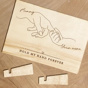 May include: A wooden sign with a line drawing of an adult hand holding a child's hand. The text reads "Mommy" and "Your name" with the phrase "Hold my hand forever" below the drawing.
