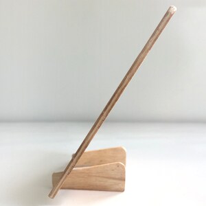 May include: A wooden easel stand with a light brown finish. The easel is made of plywood and has a simple design.