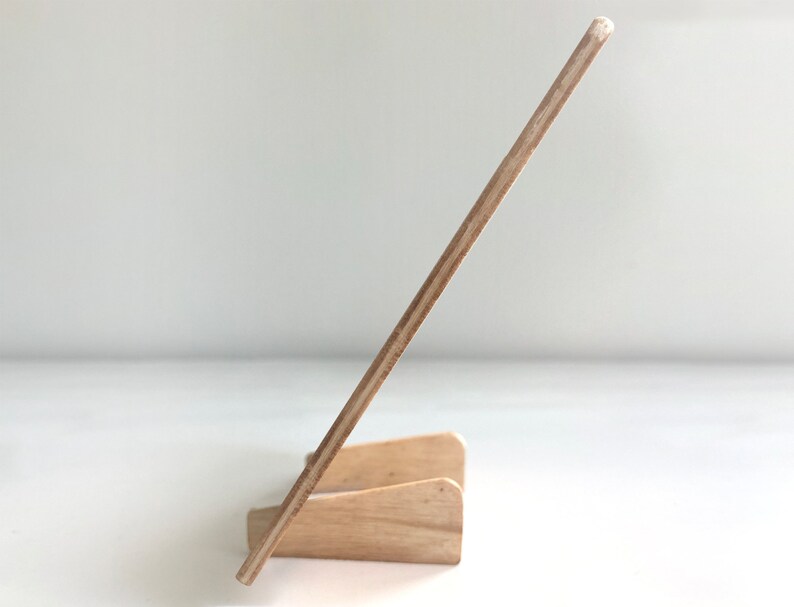 May include: A wooden easel stand with a light brown finish. The easel is made of plywood and has a simple design.