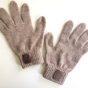 Puede incluir: Un par de guantes de punto marr&oacute;n con parches de cuero en los pu&ntilde;os. Los parches tienen las letras "L" y "O" bordadas.