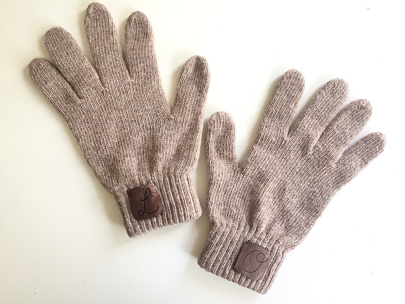 Puede incluir: Un par de guantes de punto marr&oacute;n con parches de cuero en los pu&ntilde;os. Los parches tienen las letras "L" y "O" bordadas.