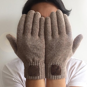 May include: A pair of brown knit gloves with leather patches on the cuffs. The patches have the letters "O" and "L" embroidered on them.