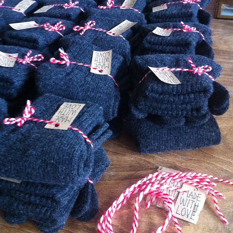 Puede incluir: Una pila de calcetines de punto azul oscuro envueltos con hilo rojo y blanco y una etiqueta que dice "Made with Love".