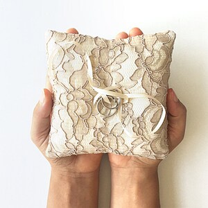 May include: A white lace ring pillow with two silver rings tied with a white satin ribbon.