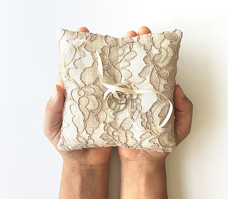 May include: A white lace ring pillow with two silver rings tied with a white satin ribbon.