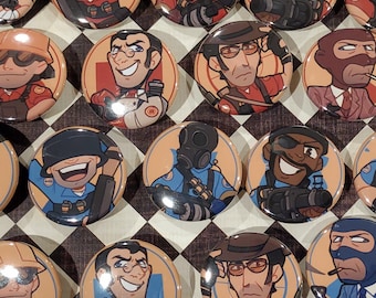 May include: A set of 16 round button pins featuring cartoon characters from the video game Team Fortress 2. The pins are on a checkered black and white surface.