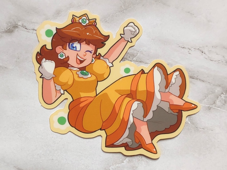 May include: A cartoon illustration of Princess Daisy from the Super Mario franchise. She is wearing a yellow dress with a green gem, a crown, and white gloves. She is smiling and has her arms raised in the air.