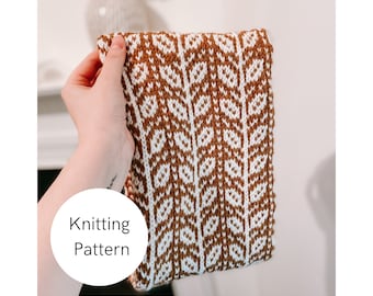 May include: A brown and white knitted scarf with a leaf pattern. The scarf is held in a hand and the text "Knitting Pattern" is visible in a circle.