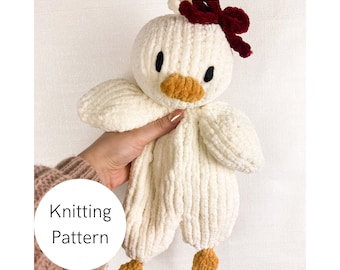 May include: Knitted white plush toy duck with a red bow and orange beak. The toy is being held by a hand. The text "Knitting Pattern" is written in a circle on the image.