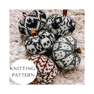 May include: Knitting pattern for five knitted pumpkins in black, white, and brown with a fair isle design. The pumpkins are on a white fluffy surface.