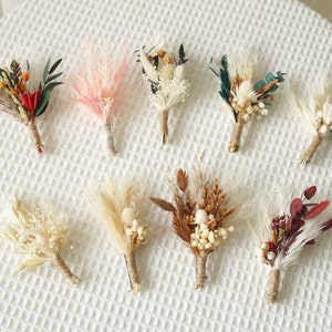 Puede incluir: Diez pequeños ramos de flores secas, cada uno atado con cuerda y con diferentes colores y texturas, incluyendo blanco, rosa, marrón, rojo y verde.