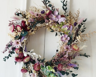 May include: A dried flower wreath with a variety of purple, pink, and burgundy flowers, eucalyptus leaves, and dried grasses.