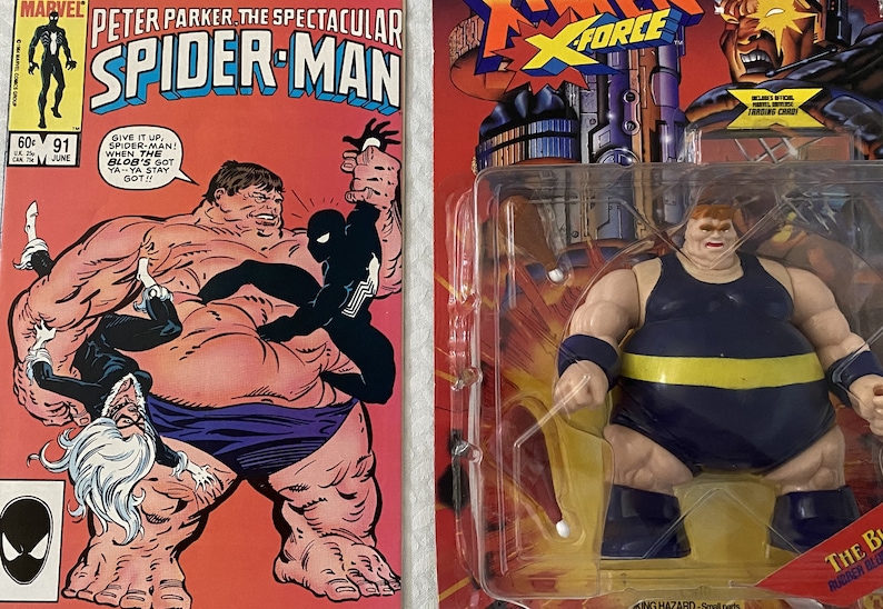 May include: A vintage comic book featuring Spider-Man battling the Blob. The comic book cover is red and features a black and white illustration of Spider-Man fighting the Blob. The comic book is titled "Peter Parker, The Spectacular Spider-Man" and is issue number 91.  The comic book is next to a plastic-wrapped action figure of the Blob. The action figure is wearing a blue and yellow costume and is holding a pair of white nunchucks. The action figure is packaged in a plastic blister pack with a red, yellow, and black background. The packaging includes the text "X-Force" and "The Blob".