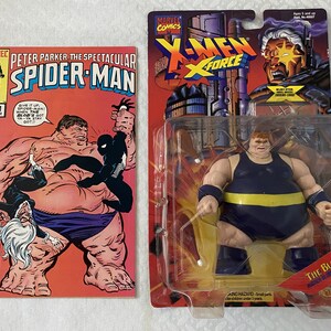 May include: A vintage action figure of The Blob from the X-Men comic book series. The figure is wearing a blue and yellow costume and is posed in a standing position. The figure is packaged in a plastic blister pack with a cardboard backing. The packaging features a comic book cover image of The Blob.