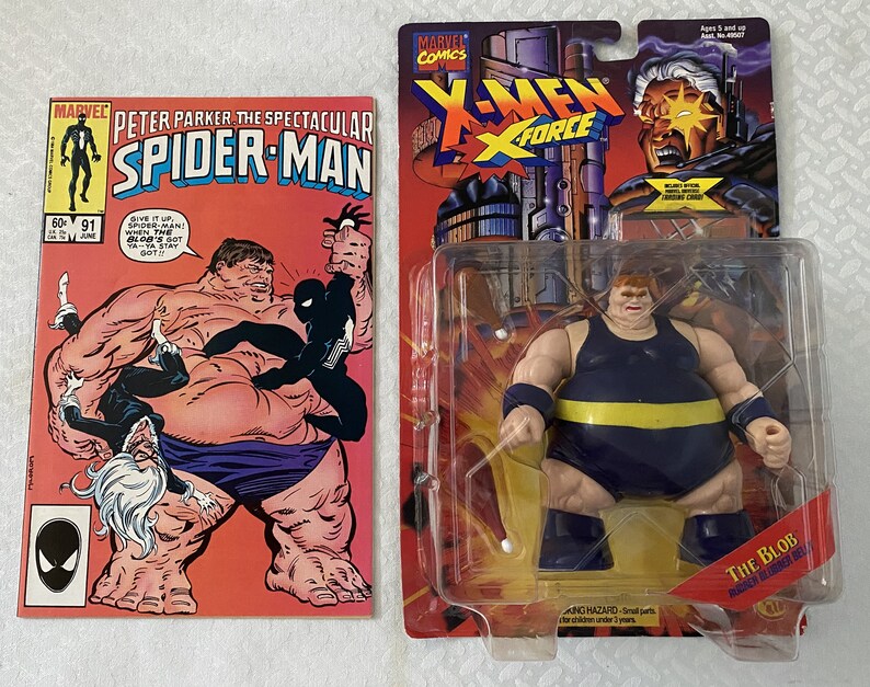 May include: A vintage action figure of The Blob from the X-Men comic book series. The figure is wearing a blue and yellow costume and is posed in a standing position. The figure is packaged in a plastic blister pack with a cardboard backing. The packaging features a comic book cover image of The Blob.