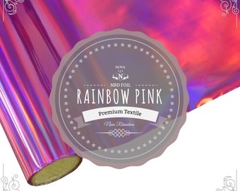 May include: A roll of iridescent rainbow pink holographic heat transfer vinyl. The vinyl is labeled "Nova NRD Foil Rainbow Pink Premium Textile Nova Rhinestone".
