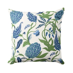 May include: A white throw pillow with a blue and green floral pattern. The pattern features stylized flowers, leaves, and vines.