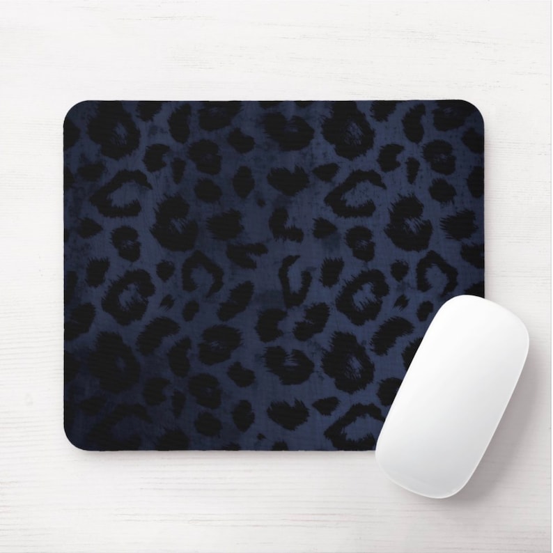 Puede incluir: Una alfombrilla de rat&oacute;n azul oscuro con un dise&ntilde;o de estampado de leopardo negro. La alfombrilla de rat&oacute;n est&aacute; sobre una superficie de madera blanca.