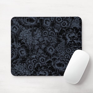 May include: A black mousepad with a floral design in shades of gray and white. The pattern features detailed illustrations of various flowers. A white wireless mouse is next to the mousepad on a white surface.
