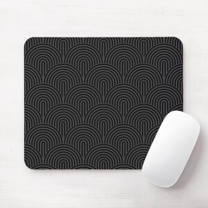 May include: A black and gray geometric patterned mouse pad with a white computer mouse on top of it.
