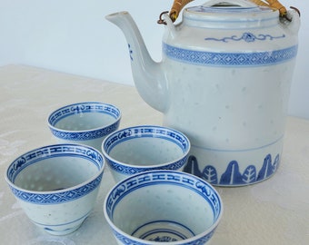 May include: A white teapot with a blue and white floral design and a woven handle, along with four matching teacups.